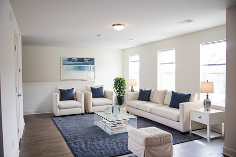 A living room with a white couch, two chairs, and a glass coffee table.