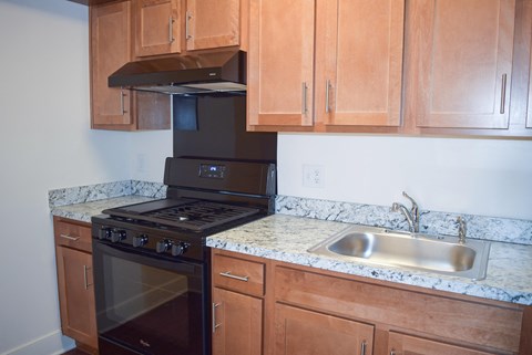 a kitchen with wooden cabinets and black appliances and a sink
