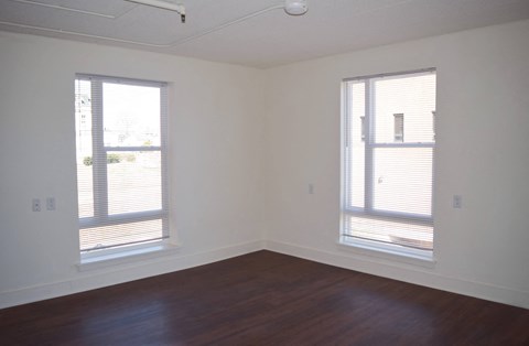 a living room with wood floors and two windows