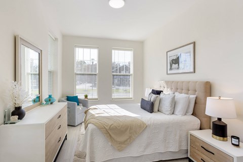 a bedroom with a bed and a dresser and three windows