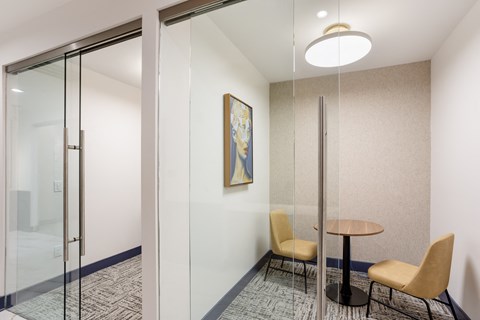 a meeting room with glass walls and a table and chairs