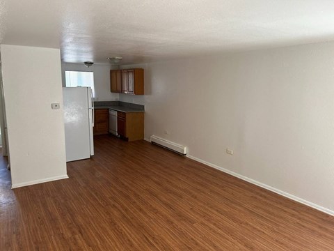 A kitchen with white walls and wooden floors.