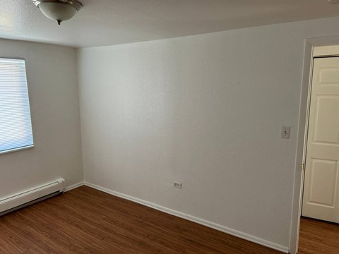 A room with a white wall and a wooden floor.