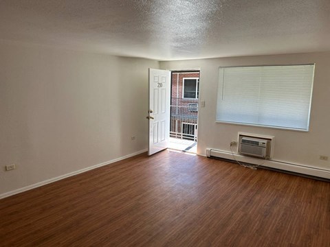 A room with wooden floors and a door leading to a balcony.