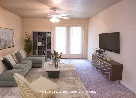 Spacious living area with a ceiling fan and plush carpeting