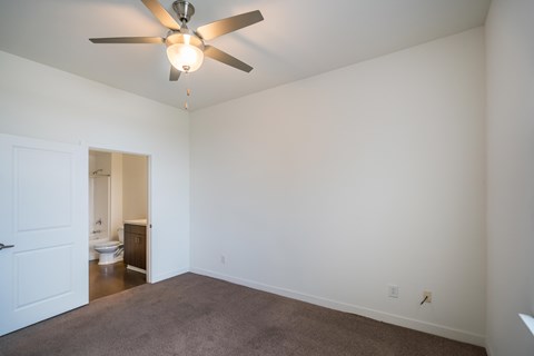 A room with a ceiling fan and carpeted floor.
