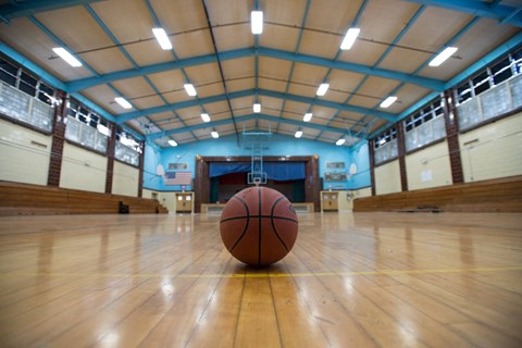 A basketball is on the court in an indoor gym.
