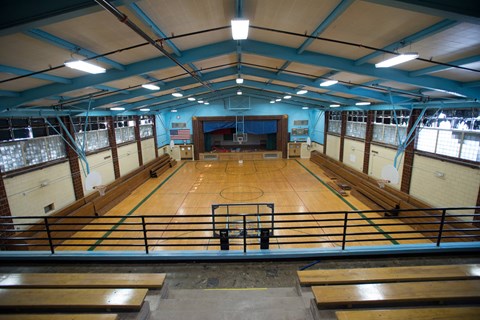 A basketball court inside a gymnasium with wooden benches.