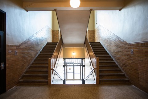 A staircase with a metal railing and wooden steps leads to a door at the bottom.