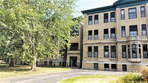 A large building with a green roof and a tree in front of it.