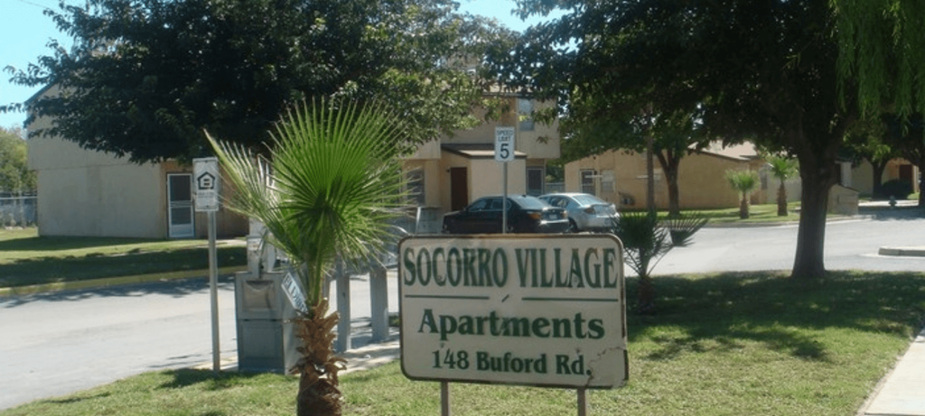 A sign for SoCroKro Village Apartments stands in front of a tree.
