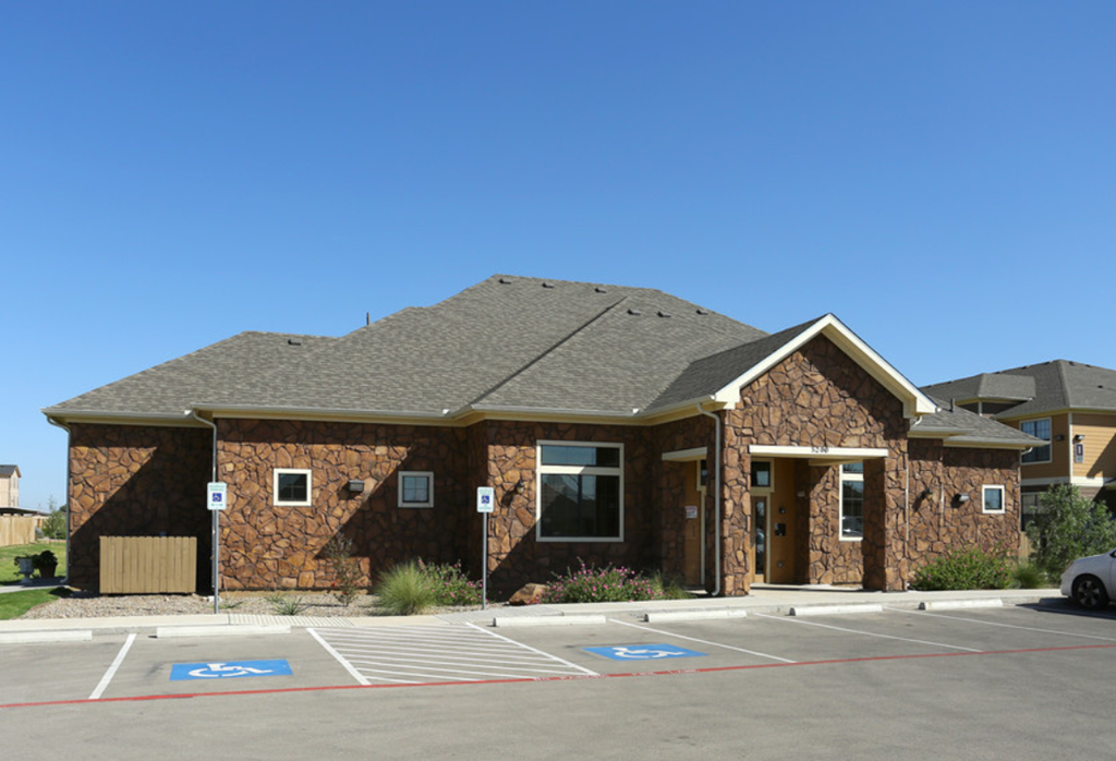 the front of a brick building with a parking lot