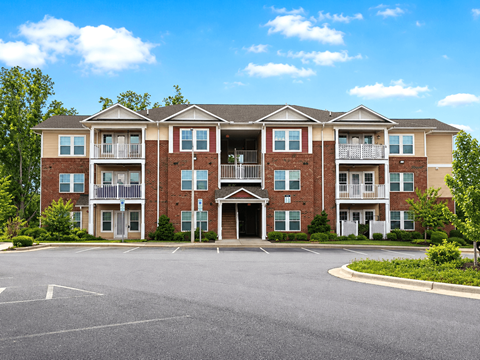 A large apartment complex with a parking lot in front.