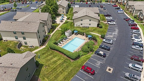 A parking lot with cars and a swimming pool in the middle of a residential area.