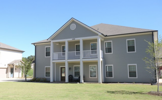 a gray house with a yard in front of it
