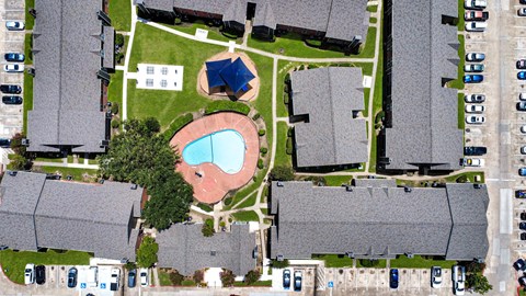 A bird's eye view of a residential area with houses, cars, and a swimming pool.