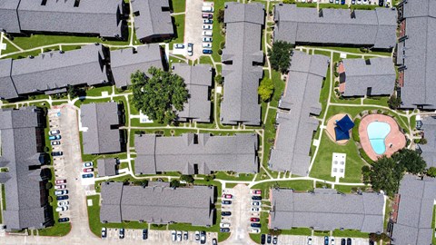 A bird's eye view of a neighborhood with houses, cars, and a playground.
