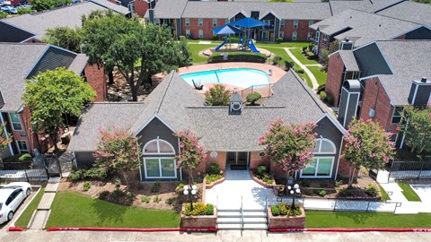 A bird's eye view of a residential area with houses, a pool, and a playground.