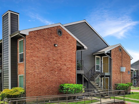 A modern brick house with a grey roof and a balcony.