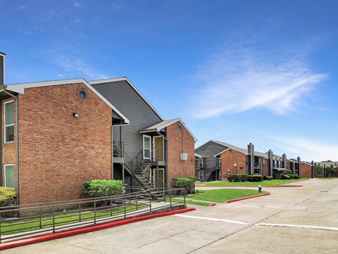 A row of modern brick apartment buildings with green lawns in front.