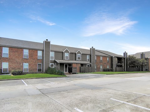 A large brick building with a parking lot in front.