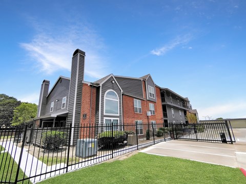A large brick building with a black fence in front.