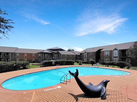 A pool with a seal statue in front of apartment buildings.