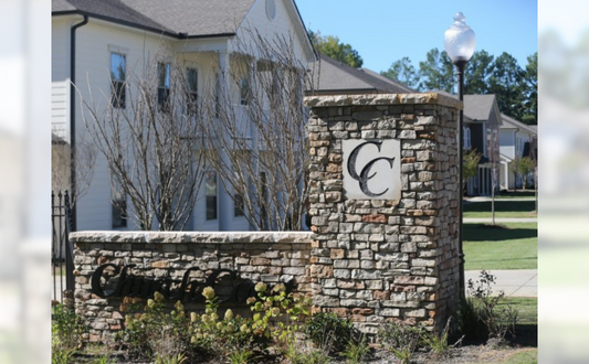 a stone wall with a cc on it in front of a house
