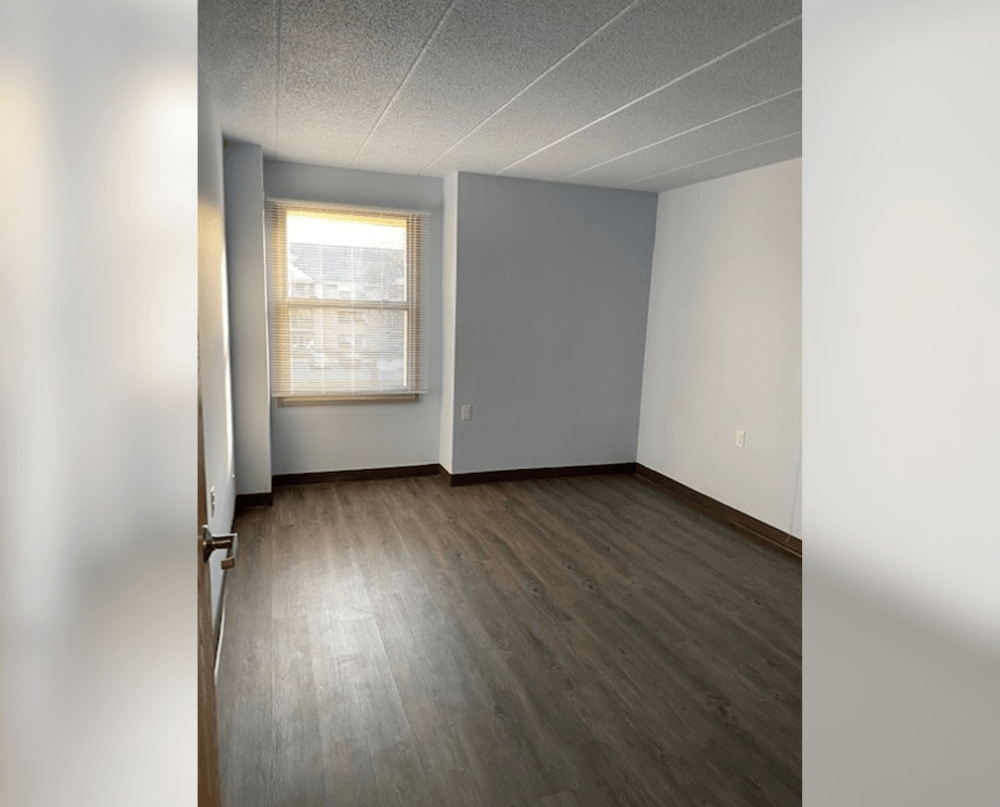 an empty room with wood floors and a window