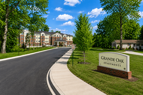 A street view of the Grande Oak Apartments with a sign in front of a grassy area.