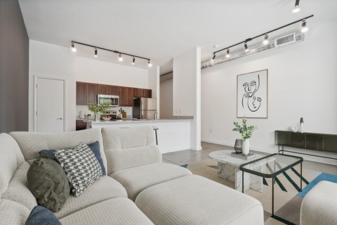A living room with a white couch and a glass coffee table.