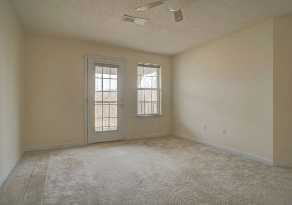 the living room of an empty house with a carpeted floor and two doors