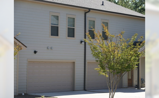 the front of a white house with two garage doors