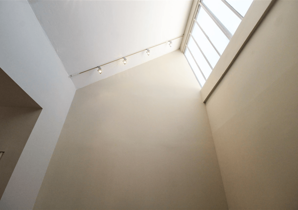A white wall with a skylight above it.