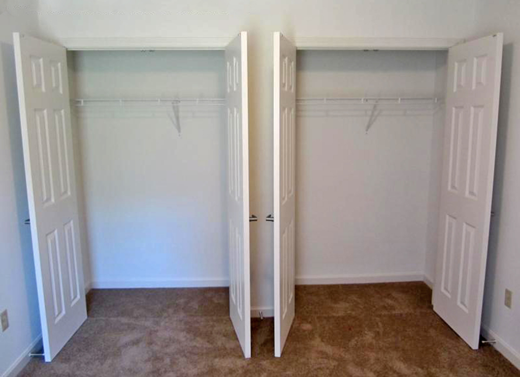 an empty bedroom with two closets and two doors