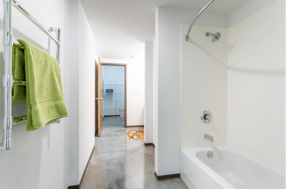 a bathroom with a white tub and a shower and a green towel