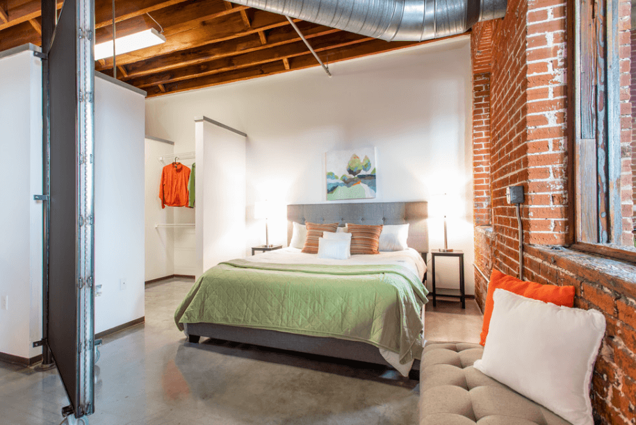 a bedroom with a bed and a exposed brick wall
