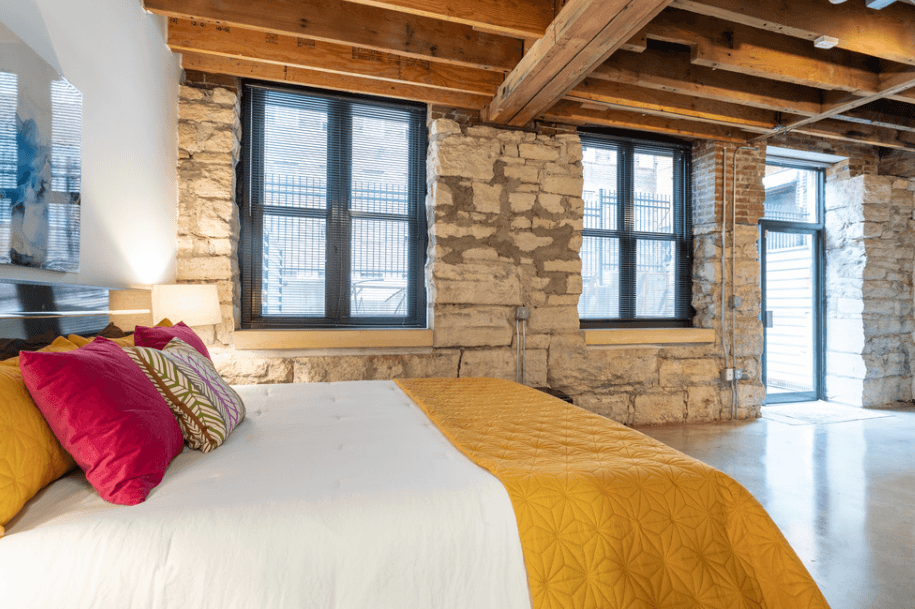 a bedroom with a bed and a stone wall