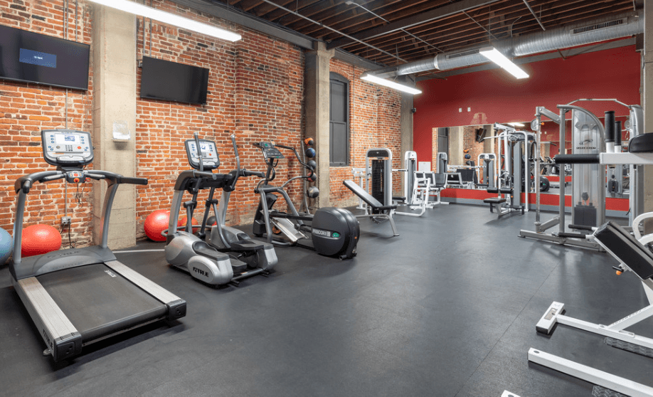 a gym with weights and cardio equipment in a brick wall