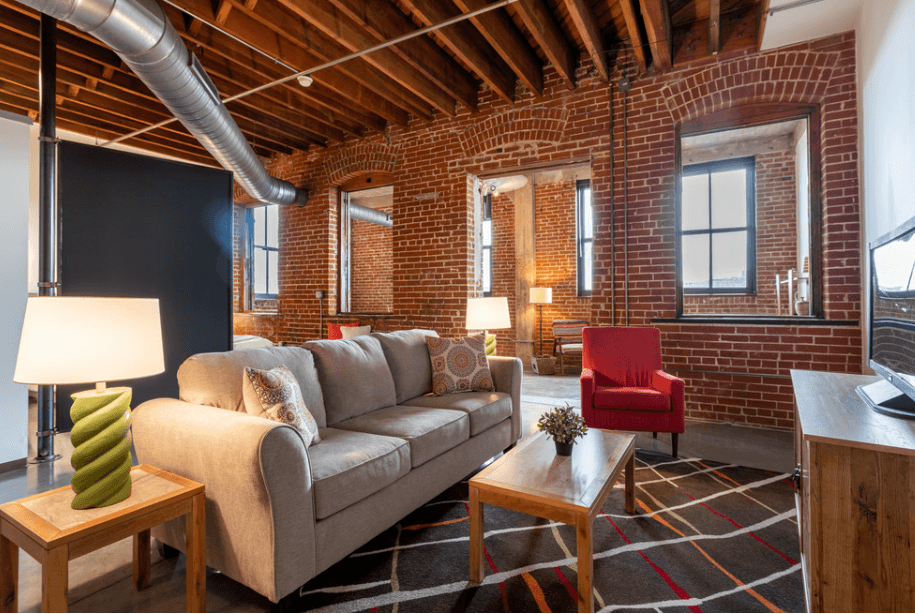 a living room with a couch in front of a brick wall