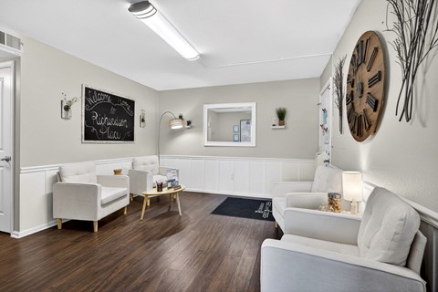 A living room with white furniture and a large clock on the wall.