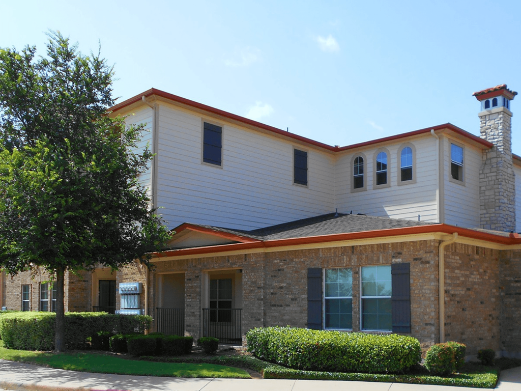 a white and brick house with a tree in front of it