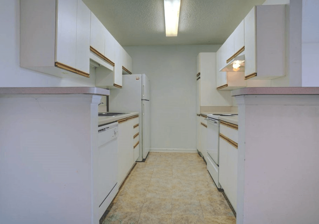 an empty kitchen with white cabinets and white appliances
