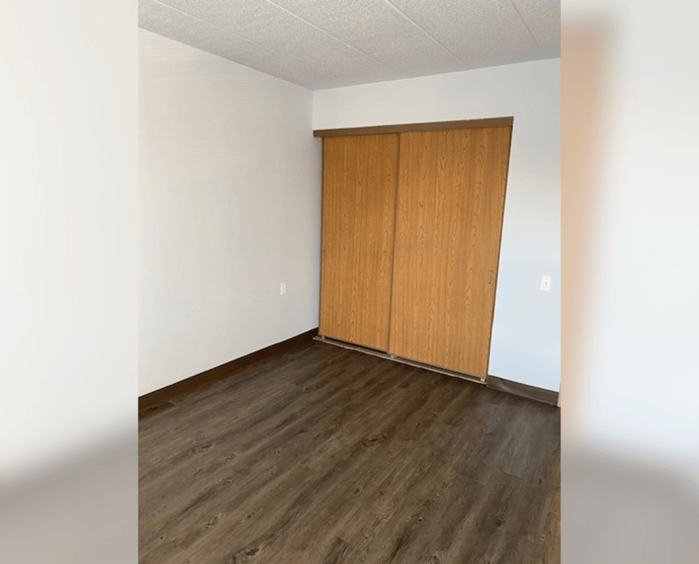 an empty room with wood floors and a closet