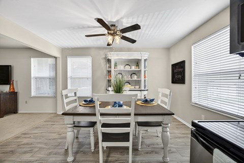 A dining room with a table set for two and a ceiling fan.