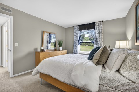 A bedroom with a large bed and a window with curtains.