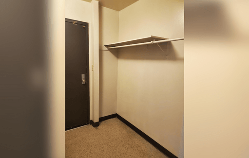 an empty room with a closet and a black door