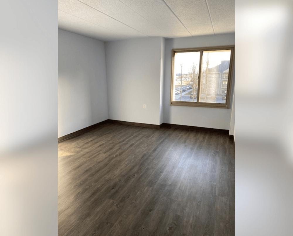 an empty living room with wood floors and a window
