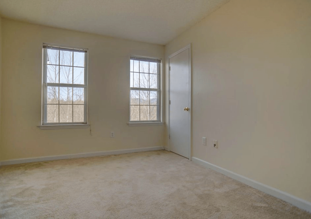 the living room of an empty house with two windows