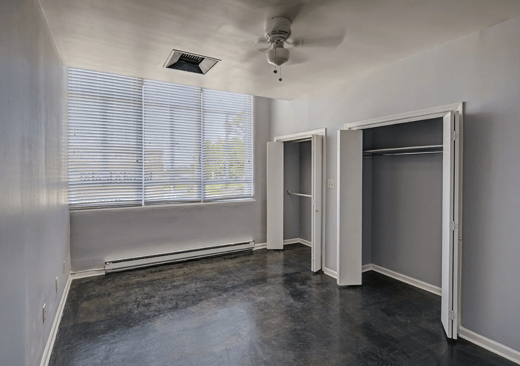 A room with a ceiling fan and a window with blinds.